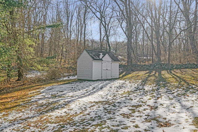 snowy yard featuring a storage shed