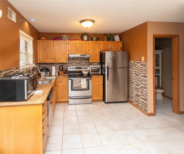 kitchen featuring light tile patterned flooring, appliances with stainless steel finishes, backsplash, and sink