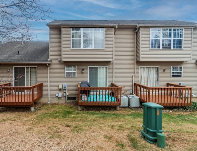 rear view of property with a lawn and central air condition unit