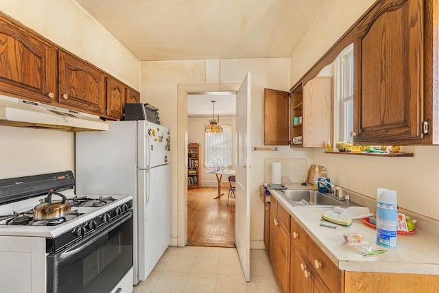 kitchen with gas range gas stove, sink, hanging light fixtures, and light hardwood / wood-style flooring