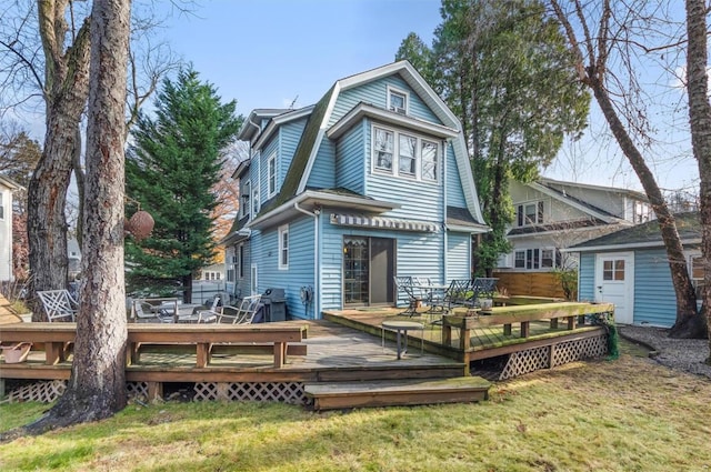 rear view of property with a lawn, a wooden deck, and a storage unit