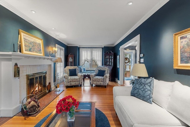 living room featuring hardwood / wood-style floors, ornamental molding, and a brick fireplace