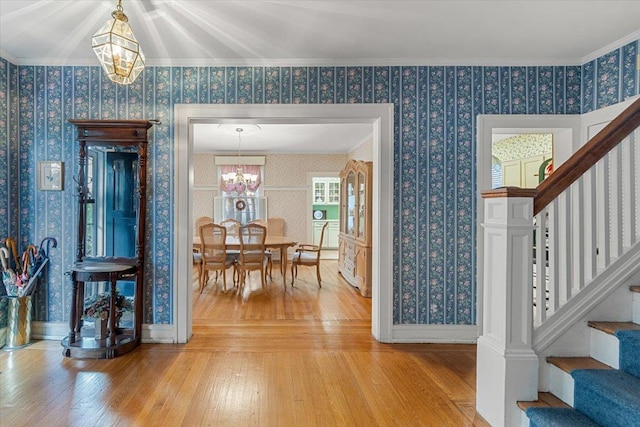 entrance foyer featuring crown molding, hardwood / wood-style floors, and a notable chandelier