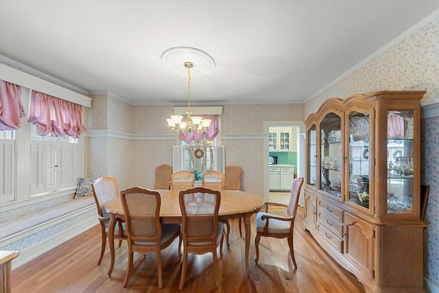 dining space featuring ornamental molding, a notable chandelier, and light wood-type flooring