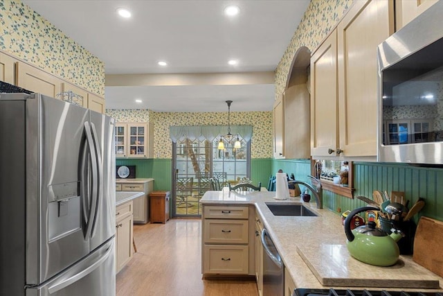 kitchen featuring sink, stainless steel appliances, an inviting chandelier, pendant lighting, and light wood-type flooring