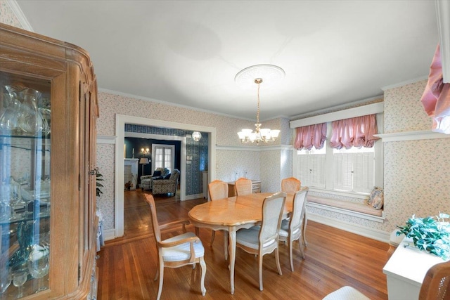 dining space with hardwood / wood-style floors, crown molding, and a chandelier