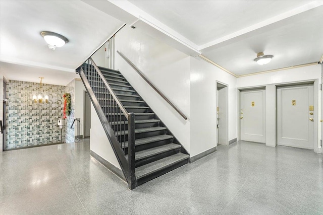 staircase with tile walls and a chandelier