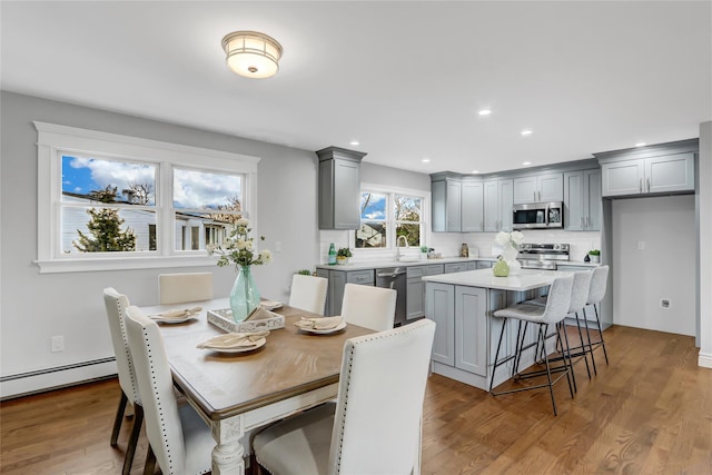 dining space featuring light hardwood / wood-style floors, baseboard heating, and sink