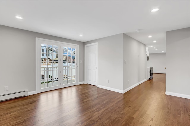 empty room featuring dark hardwood / wood-style floors and a baseboard heating unit