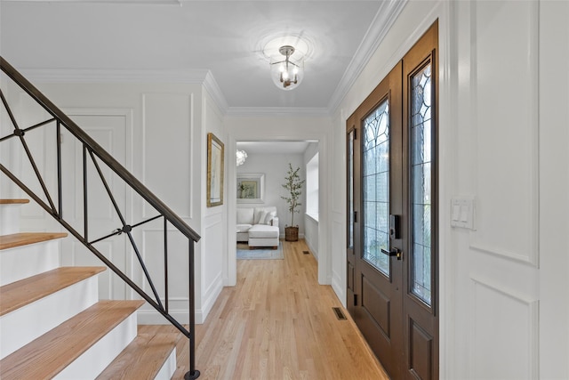 foyer with light hardwood / wood-style flooring, an inviting chandelier, and crown molding