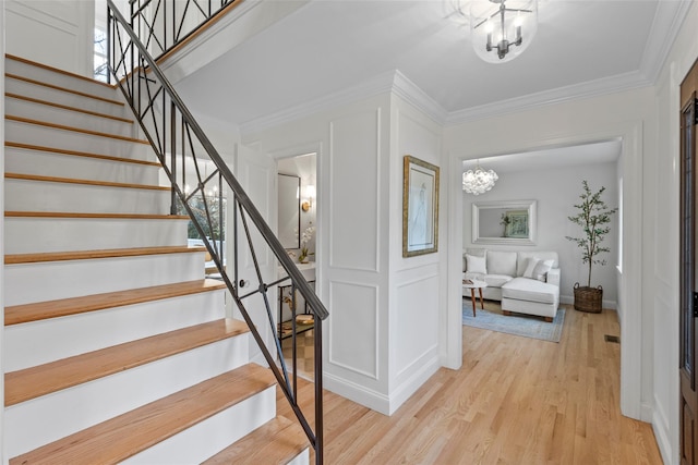 stairs with hardwood / wood-style floors, an inviting chandelier, and crown molding