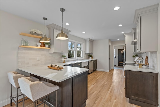 kitchen with a breakfast bar, backsplash, hanging light fixtures, kitchen peninsula, and white cabinetry