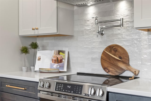 kitchen featuring decorative backsplash, gray cabinets, white cabinetry, and electric stove