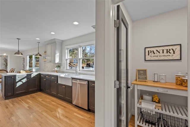 kitchen featuring dishwasher, kitchen peninsula, hanging light fixtures, and a wealth of natural light