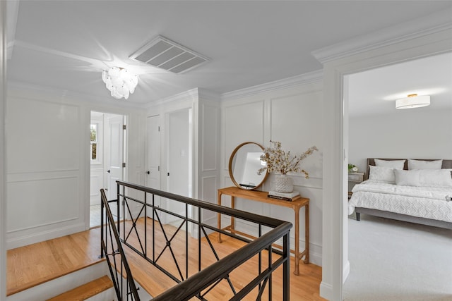 hallway with light hardwood / wood-style floors, ornamental molding, and a chandelier