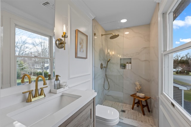 bathroom featuring toilet, vanity, and tiled shower