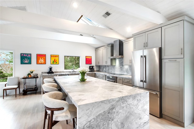 kitchen featuring gray cabinets, wall chimney range hood, a healthy amount of sunlight, and appliances with stainless steel finishes