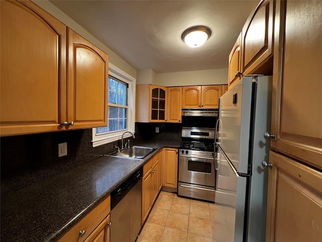 kitchen featuring light tile patterned floors, stainless steel appliances, dark stone countertops, and sink