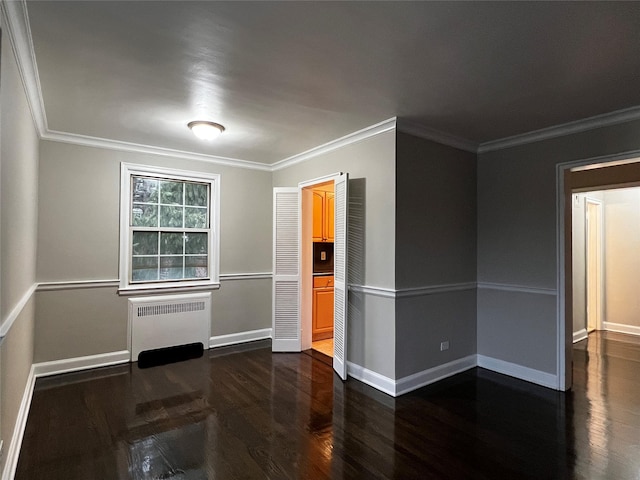 empty room with dark hardwood / wood-style flooring, radiator, and ornamental molding