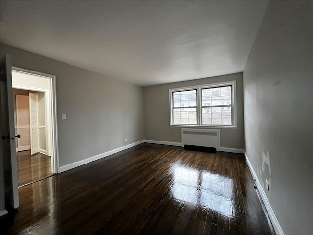 empty room featuring radiator heating unit and dark hardwood / wood-style floors