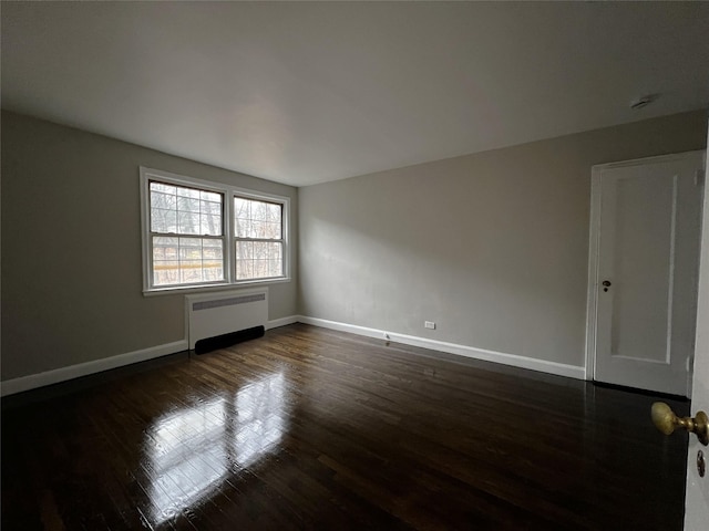 spare room featuring dark hardwood / wood-style floors and radiator