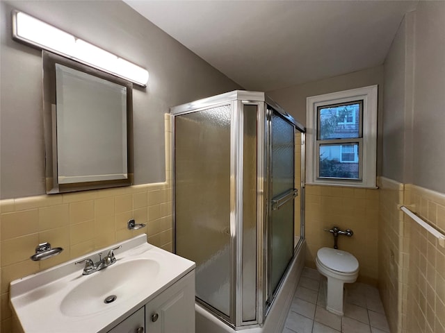 bathroom with tile patterned floors, vanity, an enclosed shower, and tile walls