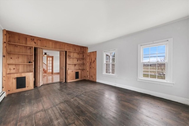 unfurnished living room with dark hardwood / wood-style flooring, baseboard heating, and crown molding