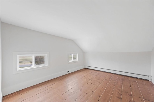 additional living space with vaulted ceiling, light hardwood / wood-style flooring, and a baseboard heating unit