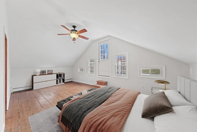 bedroom featuring light wood-type flooring, a baseboard radiator, vaulted ceiling, and multiple windows