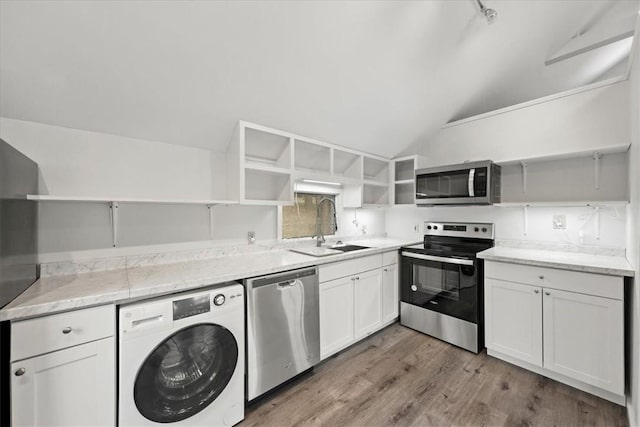 kitchen featuring stainless steel appliances, lofted ceiling, washer / dryer, white cabinets, and light wood-type flooring