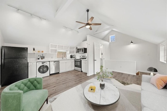 living room with sink, high vaulted ceiling, light hardwood / wood-style floors, track lighting, and washer / dryer