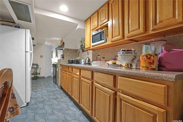 kitchen featuring ventilation hood, white refrigerator, and tasteful backsplash