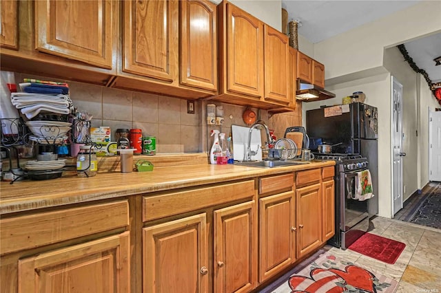 kitchen featuring black gas range oven, backsplash, and sink