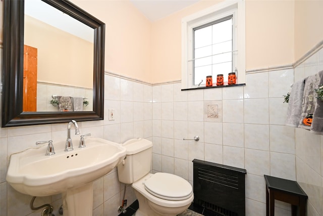 bathroom with toilet, sink, tile walls, and heating unit