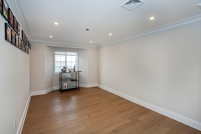 empty room with hardwood / wood-style floors and crown molding