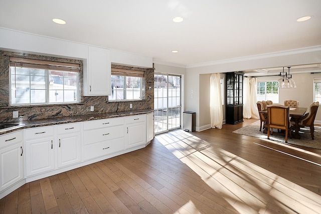 kitchen featuring tasteful backsplash, hanging light fixtures, white cabinets, and wood-type flooring