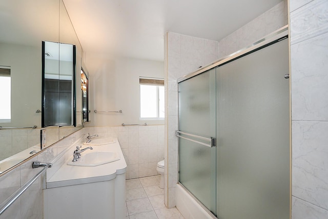 full bathroom featuring vanity, shower / bath combination with glass door, tile walls, tile patterned flooring, and toilet