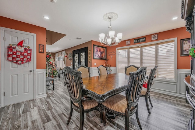 dining space with light hardwood / wood-style flooring and a chandelier