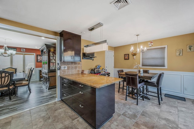 kitchen with dark brown cabinets, light wood-type flooring, decorative light fixtures, and an inviting chandelier