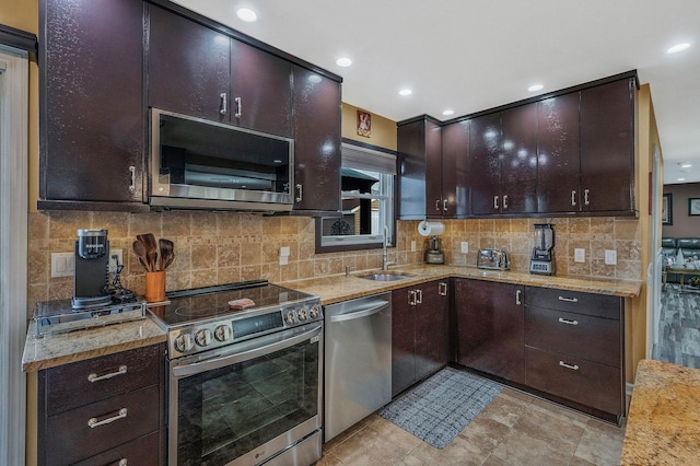 kitchen featuring sink, decorative backsplash, appliances with stainless steel finishes, light stone counters, and dark brown cabinetry