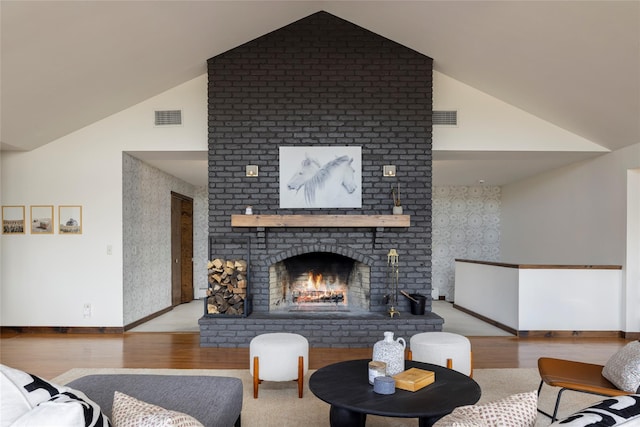 living room featuring a brick fireplace, light wood-type flooring, and vaulted ceiling