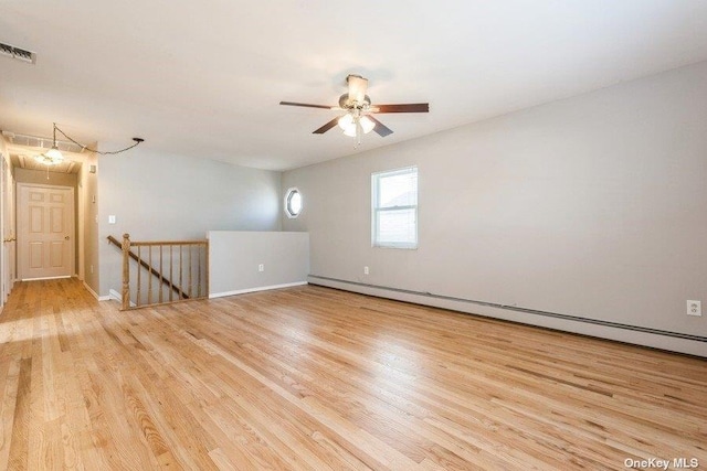 spare room with a baseboard heating unit, ceiling fan, and light wood-type flooring