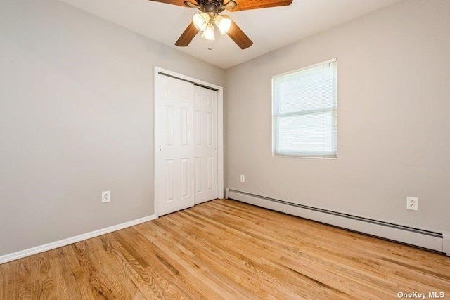 unfurnished bedroom with a baseboard radiator, light wood-type flooring, ceiling fan, and a closet