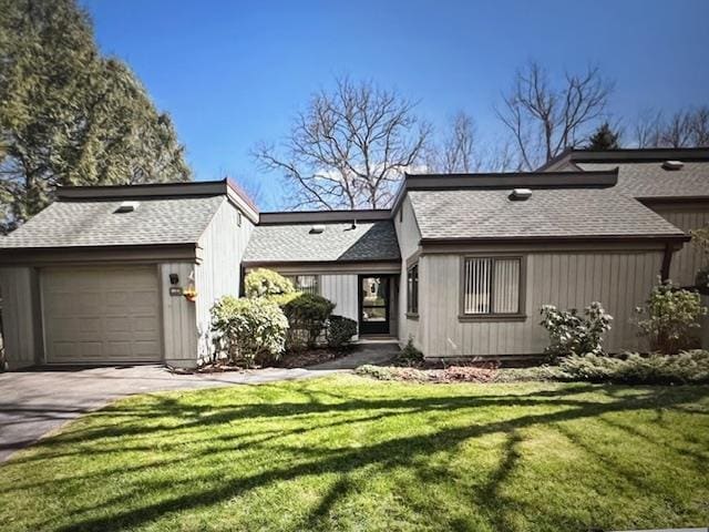 rear view of property with a garage and a lawn