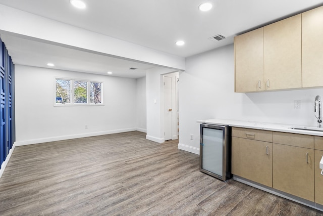 kitchen with sink, light brown cabinets, light stone counters, stainless steel fridge, and wood-type flooring