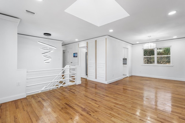 spare room featuring ornamental molding, light hardwood / wood-style floors, and a notable chandelier