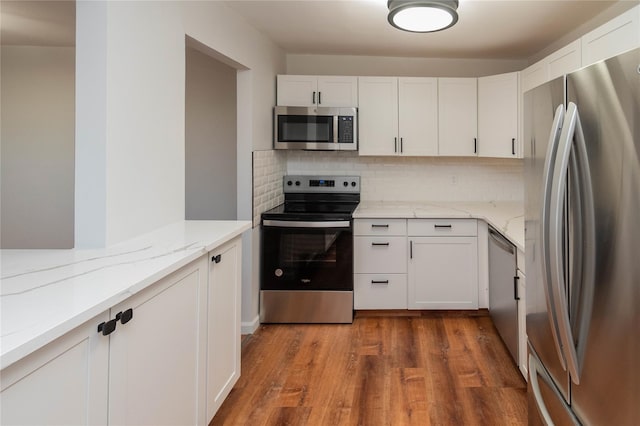 kitchen with decorative backsplash, wood finished floors, light stone countertops, stainless steel appliances, and white cabinetry