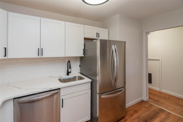 kitchen with decorative backsplash, white cabinets, appliances with stainless steel finishes, wood finished floors, and a sink