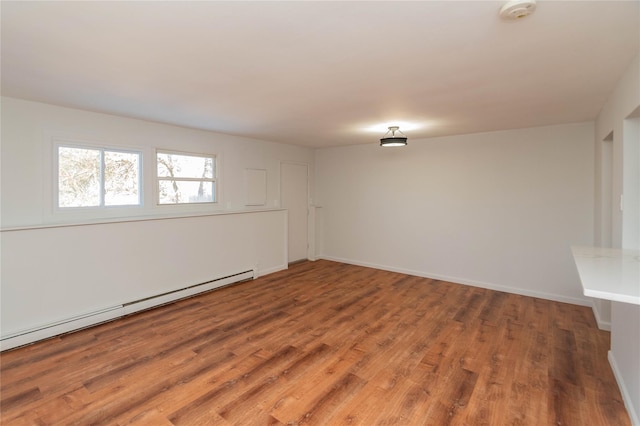 unfurnished room featuring a baseboard radiator, baseboards, and wood finished floors