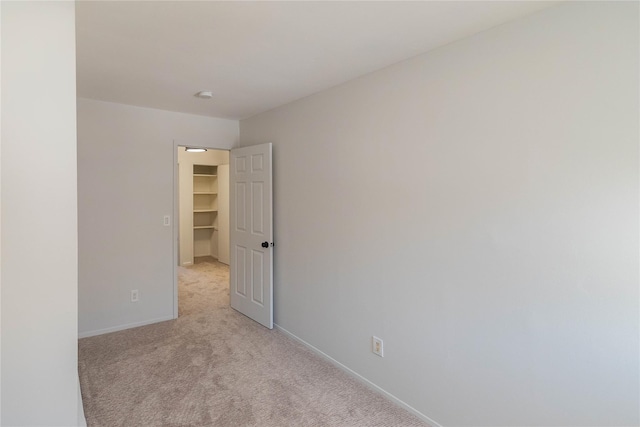 unfurnished room featuring light colored carpet and baseboards